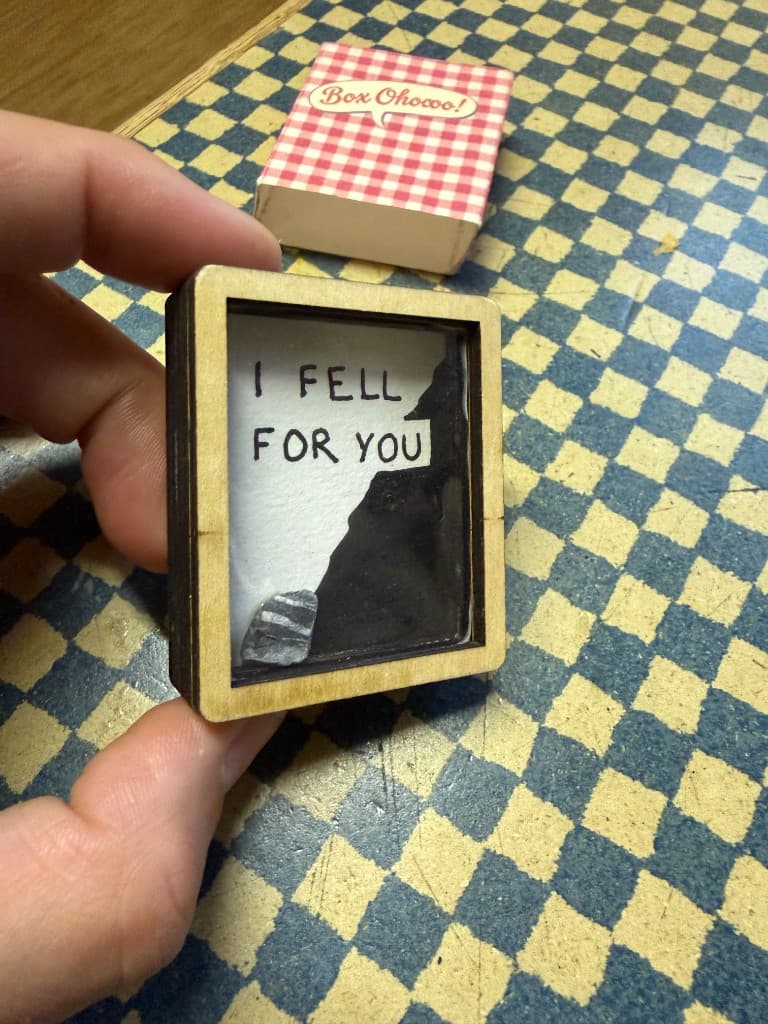 Tiny Art Surprise open in its wooden frame, held between two fingers