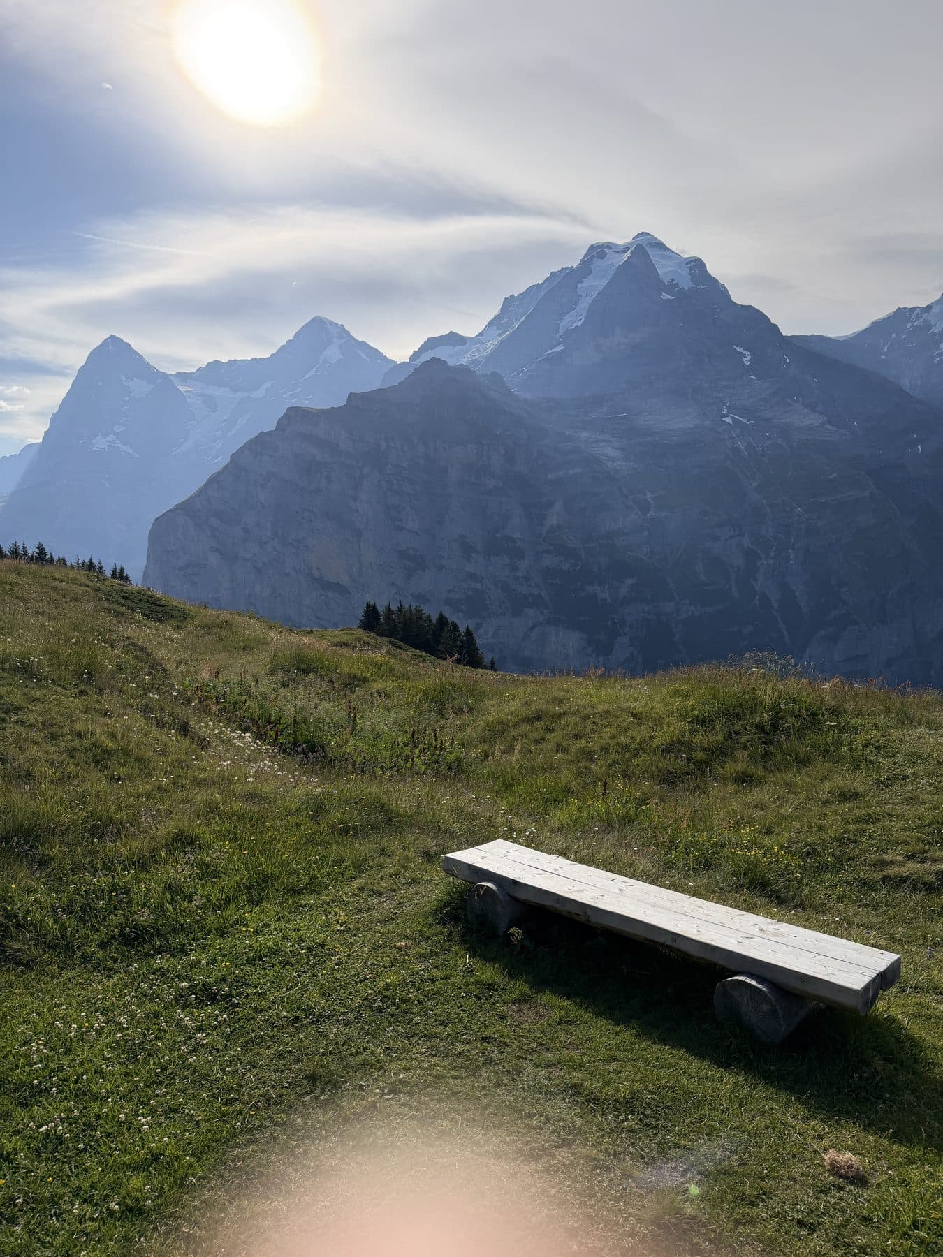 Holzbank mit Blick auf Felsen und schneebedeckte Gipfel