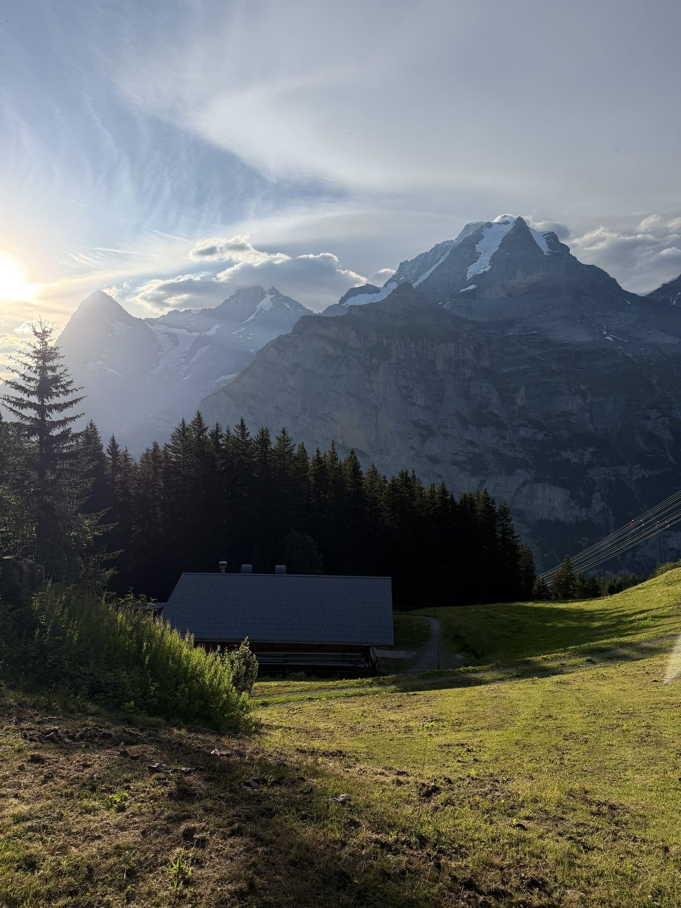 Abendlicht über einer Hütte und dem Nadelwald